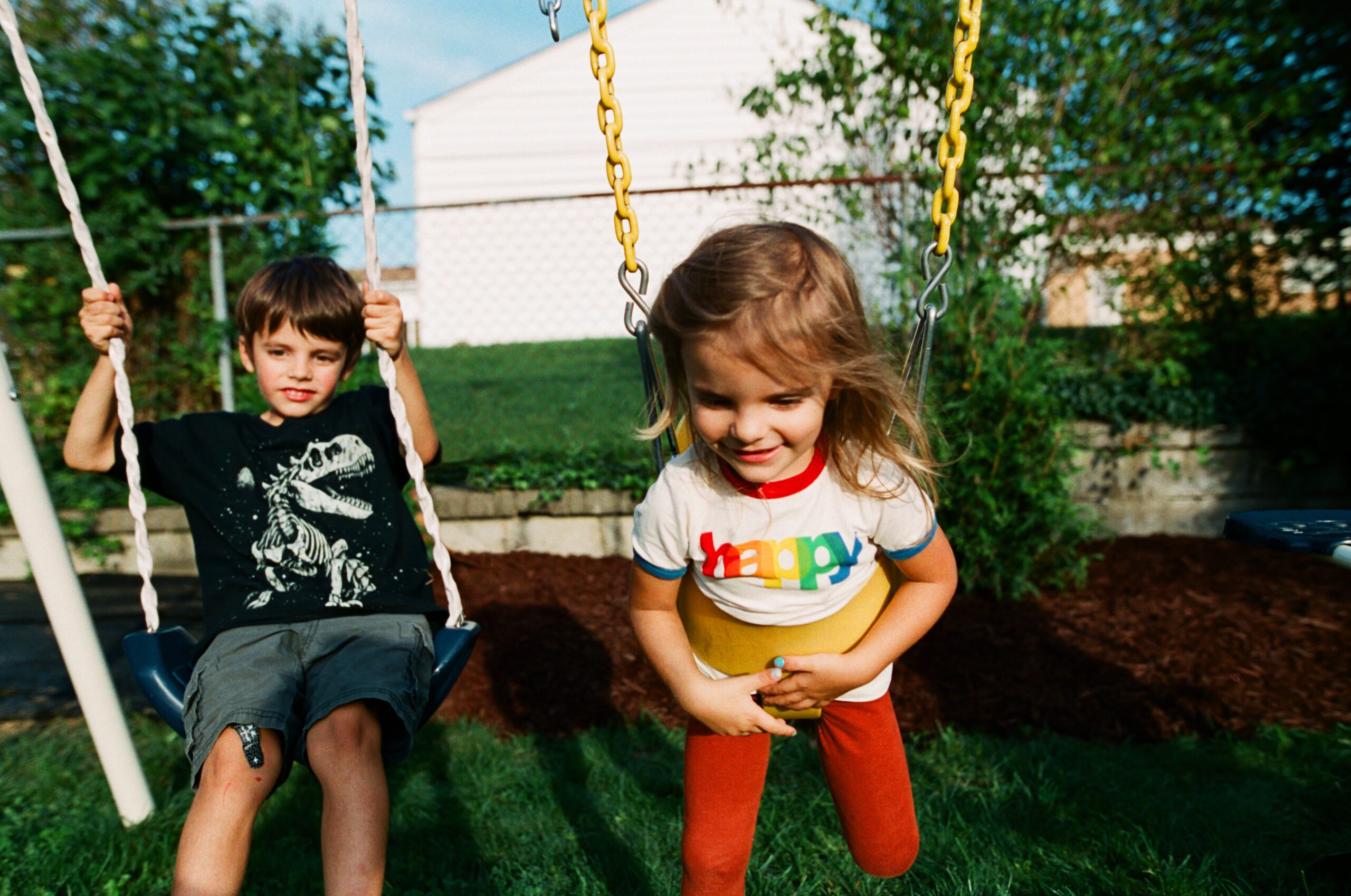 young girl and boy playing on a swing set