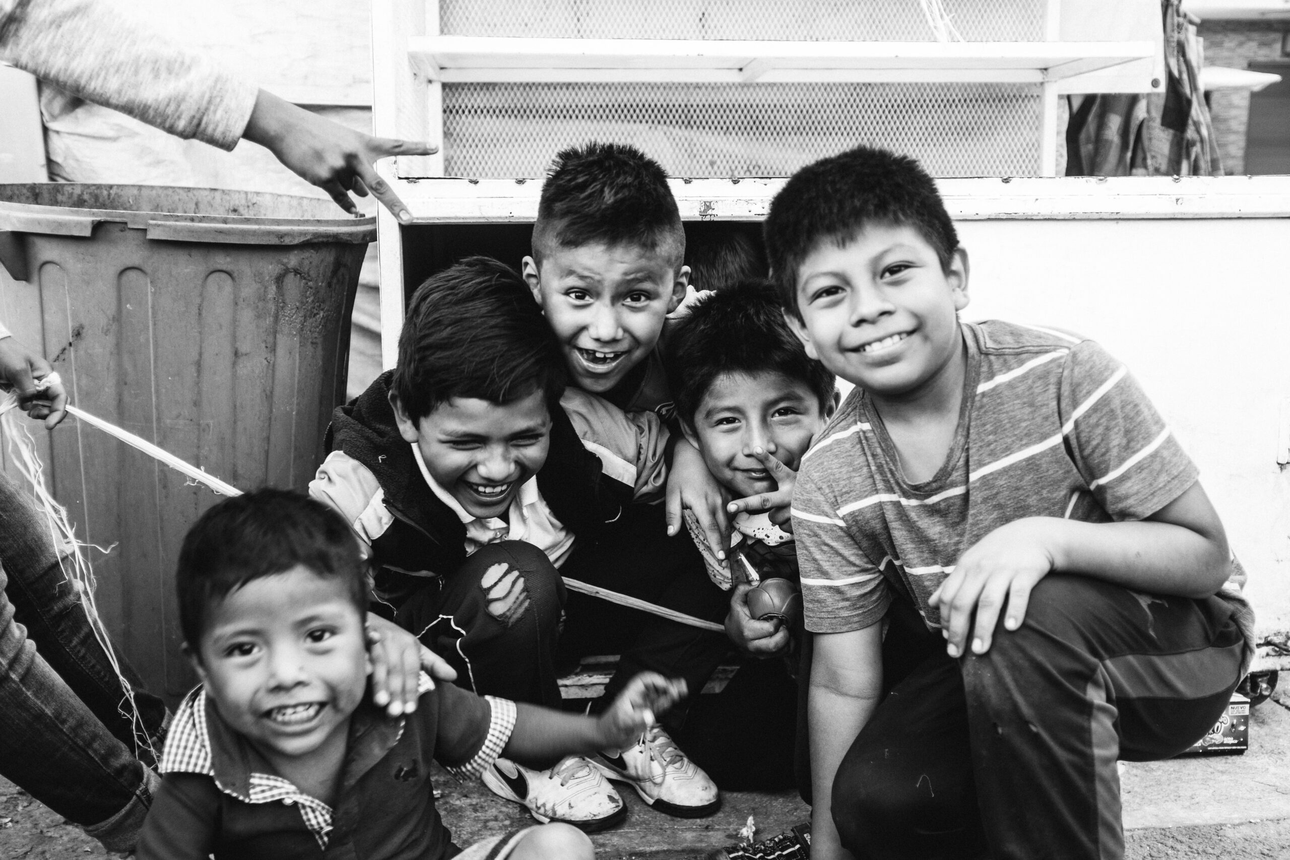 Black and white photo of a group of kids, smiling at the camera.